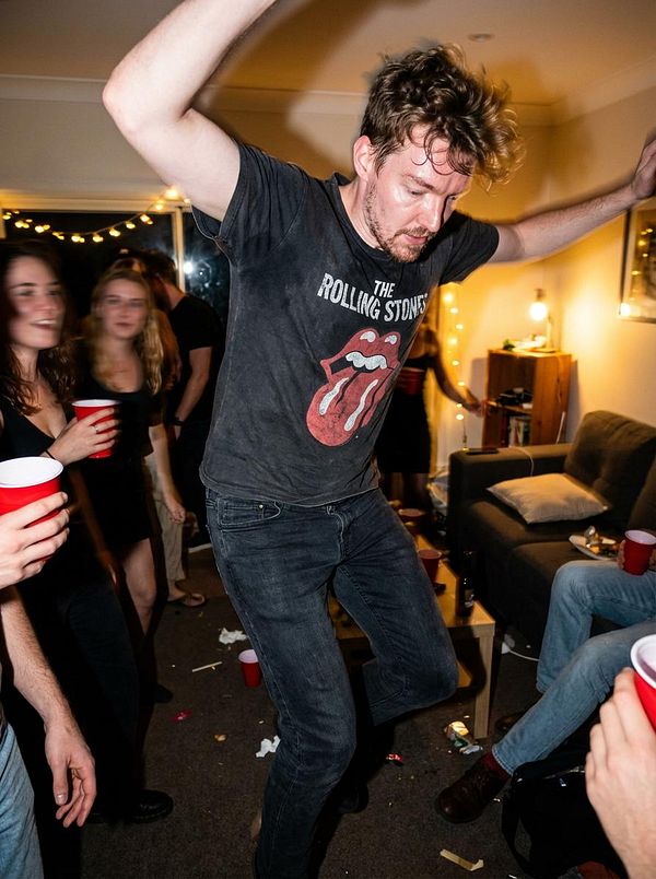 A lively party scene featuring a man dancing energetically among friends.