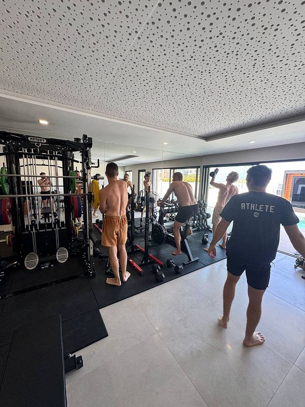 A group of individuals is engaged in a workout session in a modern gym environment.