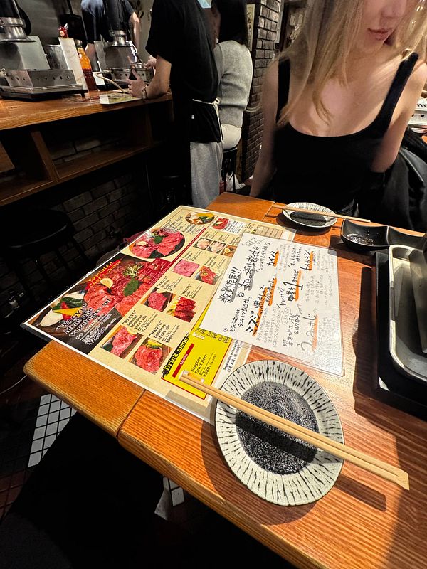 A table setting in a restaurant featuring a menu for wagyu beef and a plate with chopsticks.