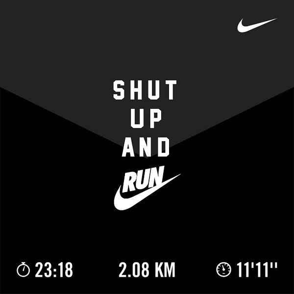 A runner is captured from behind running along a road with lush green trees and clear skies, showcasing a mid-run outdoor exercise.