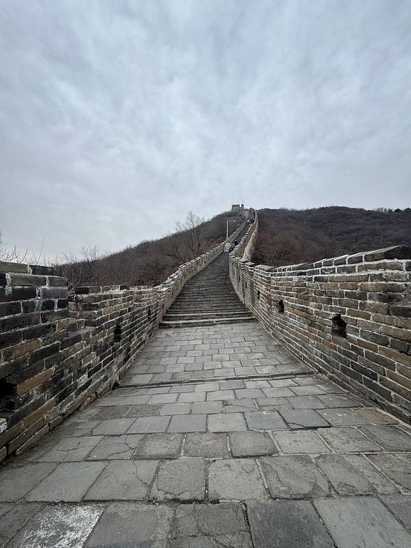 A view of a section of the Great Wall of China, showcasing its steep ascent and stone pathway.