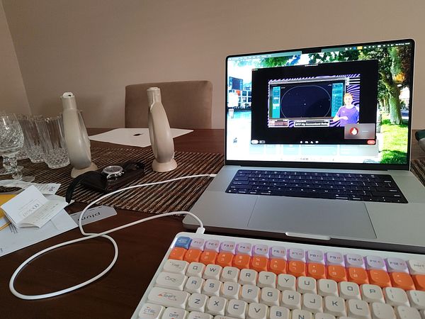 A laptop displaying a video call with a layout update discussion, surrounded by various items on a table.