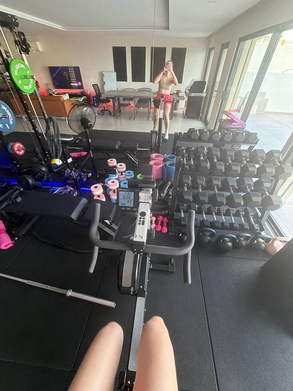 A person performing a one-arm dumbbell row in a gym setting.
