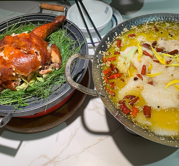 A beautifully presented dinner featuring a roasted chicken and a spicy fish dish.