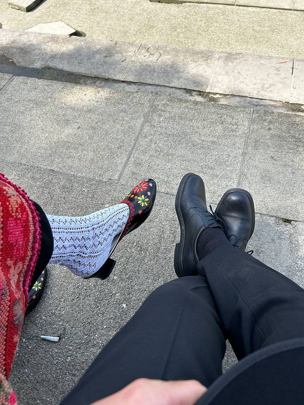 Two pairs of feet are visible, showcasing distinct footwear styles.