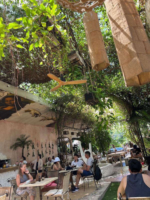 A vibrant outdoor dining area filled with greenery and patrons enjoying their meals.