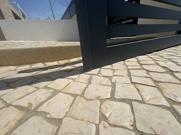 A damaged electric gate is shown resting on the ground, unable to move.