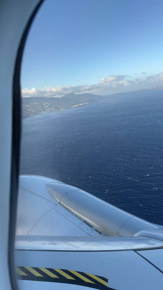 A view from an airplane window capturing the coastline of Madeira as the plane approaches landing.