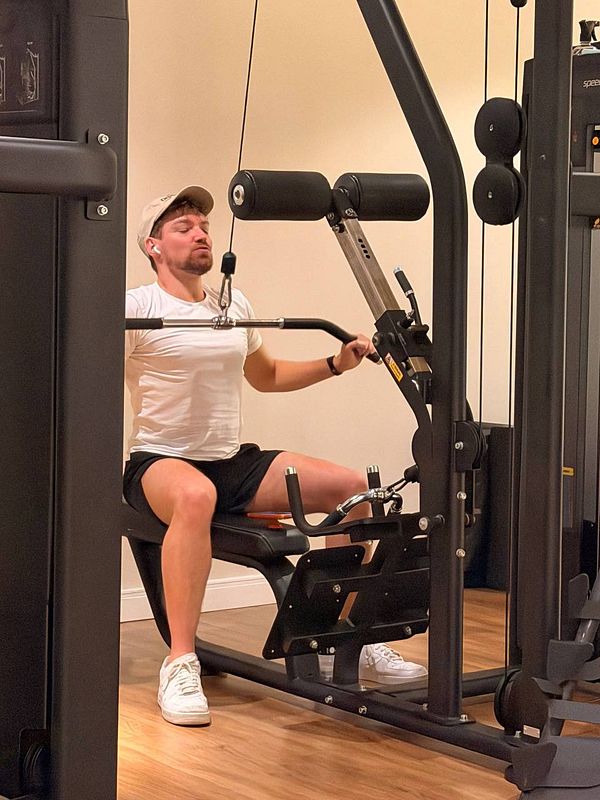 Portrait of a young woman lifting a pink dumbbell in a gym setting wearing athletic wear.