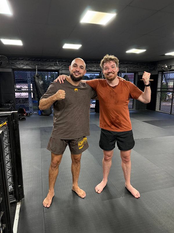 A female athlete in a gym kneeling on the floor wearing boxing gloves and athletic wear.