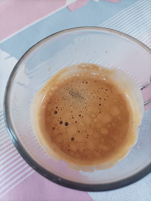 A close-up view of a glass containing freshly brewed espresso.