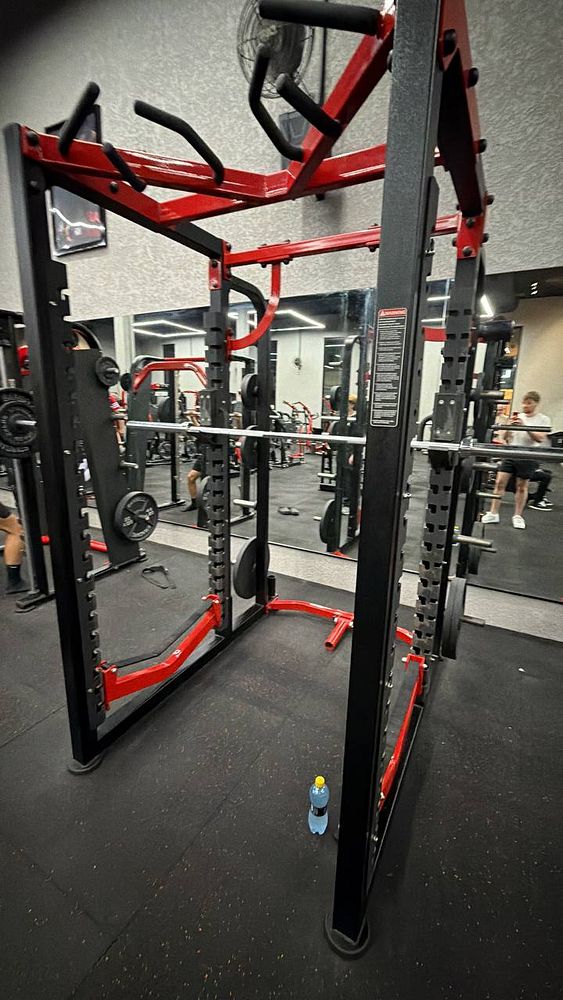 Photo of a gym workout area with exercise equipment, a dumbbell, and a bike in the foreground.