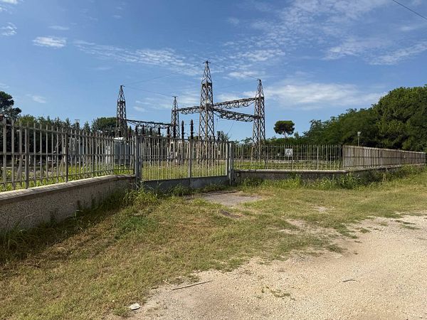 An industrial area featuring electrical towers and a fenced enclosure.