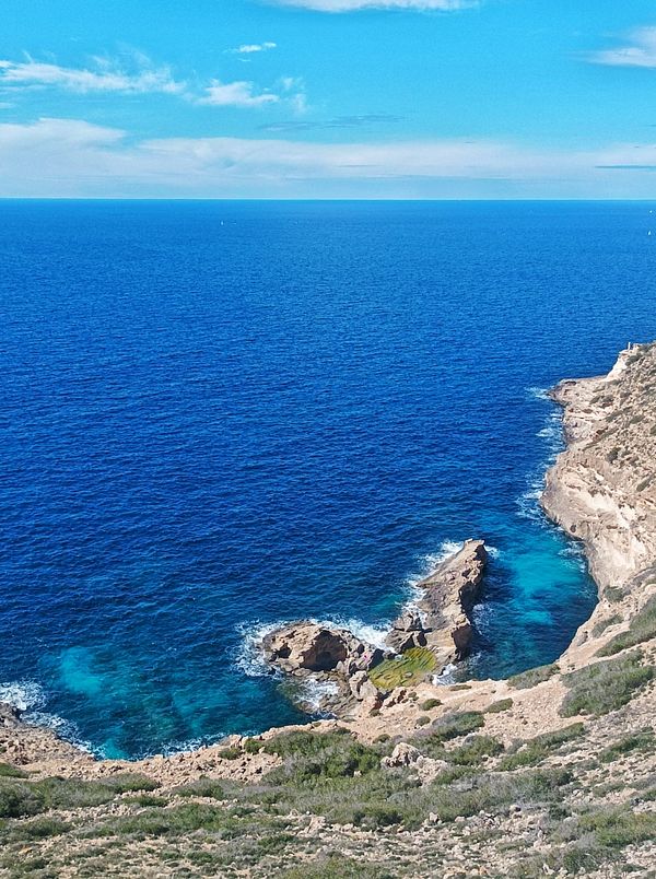 A scenic coastal view featuring rocky cliffs and vibrant blue waters.