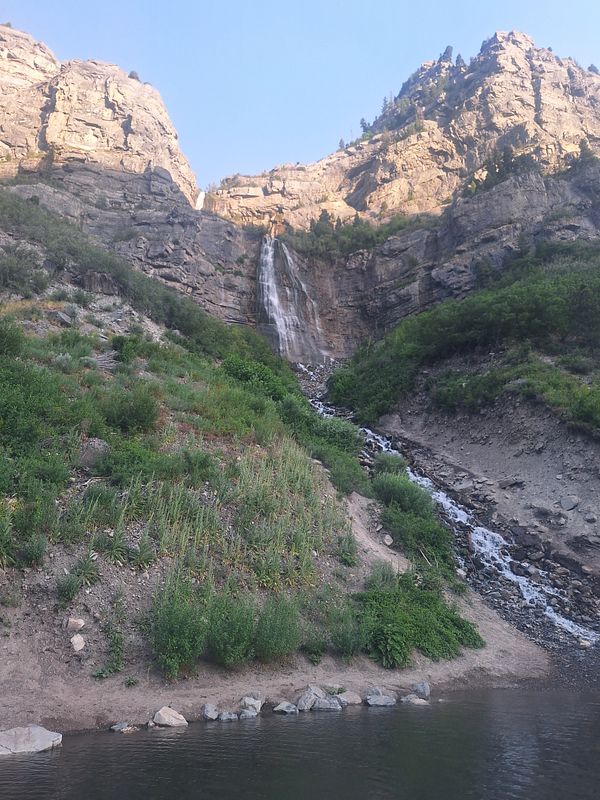 A scenic view of a waterfall cascading down rocky cliffs surrounded by lush greenery.
