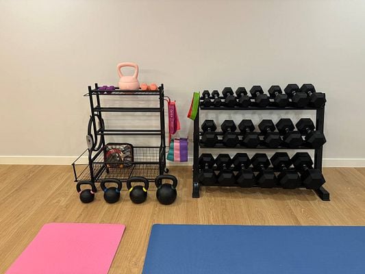 The image depicts a well-organized home gym area featuring various fitness equipment.