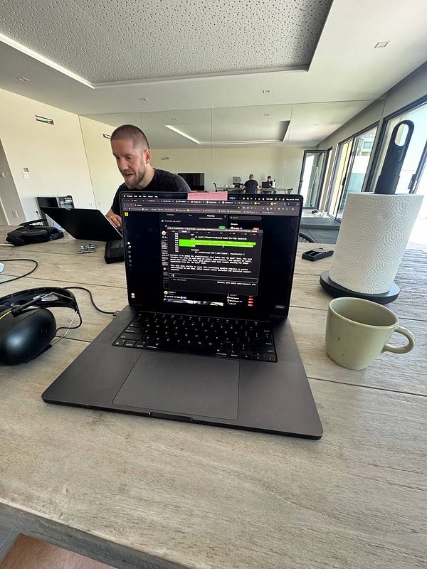 A coworking space setup featuring a laptop, a person working, and a coffee cup.