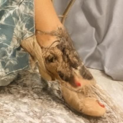 A close-up of a foot wearing a uniquely designed shoe with a floral pattern.