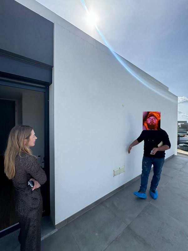 A woman and a man are discussing the installation of outside stairs to a roof on a sunny day.