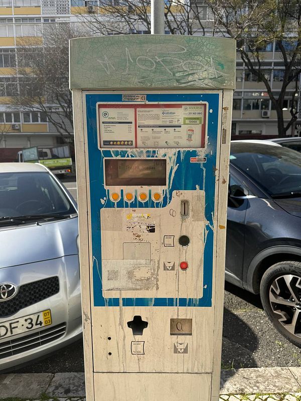 A weathered parking meter in Lisbon that only accepts coins for payment.