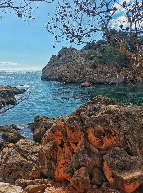 A scenic coastal view featuring rocky formations and clear blue water.