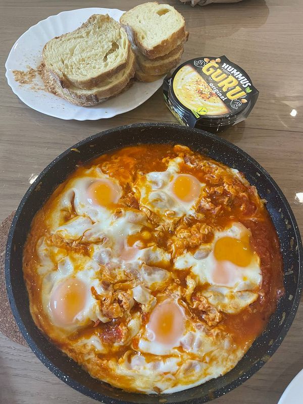 A delicious serving of shakshuka with bread and hummus on the side.