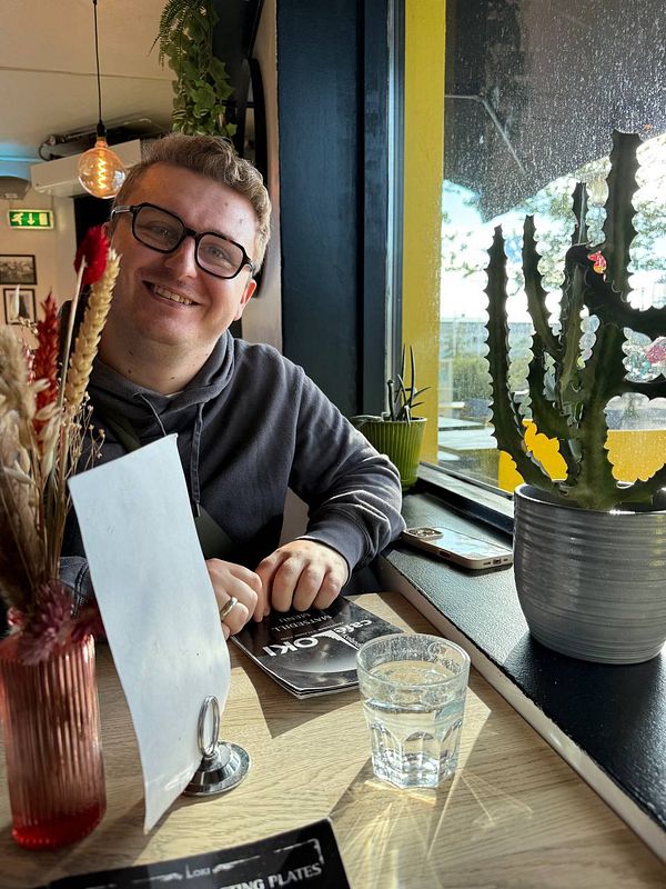 A person is sitting at a table in a café in Reykjavik, smiling and enjoying their time.