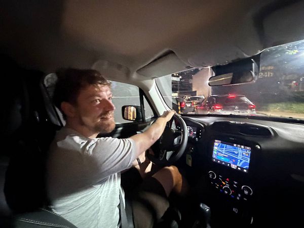A white McDonald's McDrive takeaway bag filled with food items is placed on a car seat.