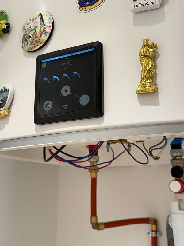 A modern water heater control panel is displayed, showcasing its connections and surrounding decor.