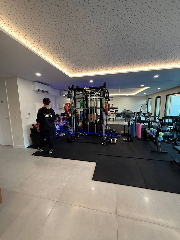 A personal gym space featuring various workout equipment and a trainer.
