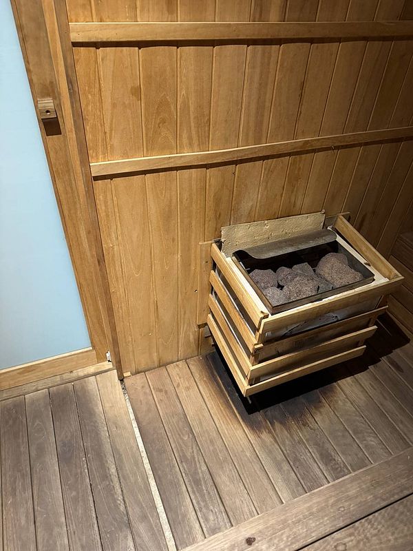 A wooden sauna interior featuring a stone heater.