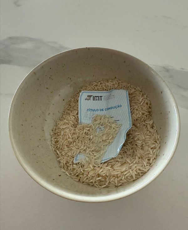 A driver's license is partially submerged in a bowl of rice.