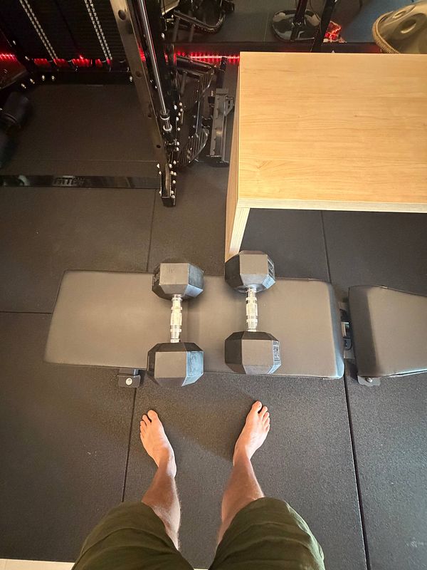 Muscular woman in a gym posing with weights beside machines and fitness equipment.