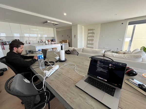 A remote coworking space featuring a man working on a laptop at a wooden table.