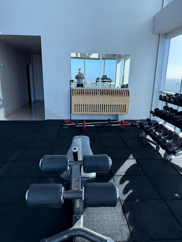 A well-equipped gym space featuring workout equipment and a large mirror.