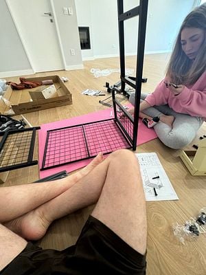 A couple is assembling a home gym equipment in a spacious room.