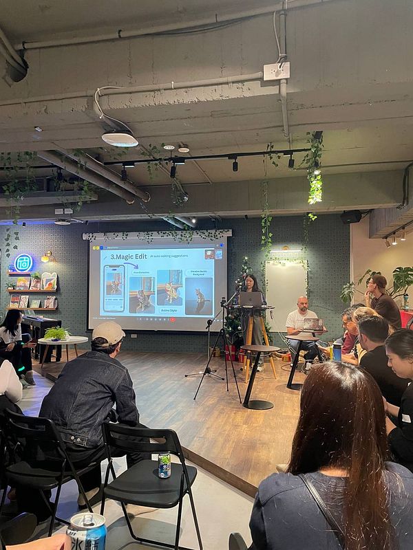 A tech event presentation featuring a speaker discussing AI tools with an audience.