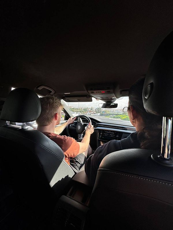 A person is driving a car for the first time in 20 years, with another individual seated beside them.