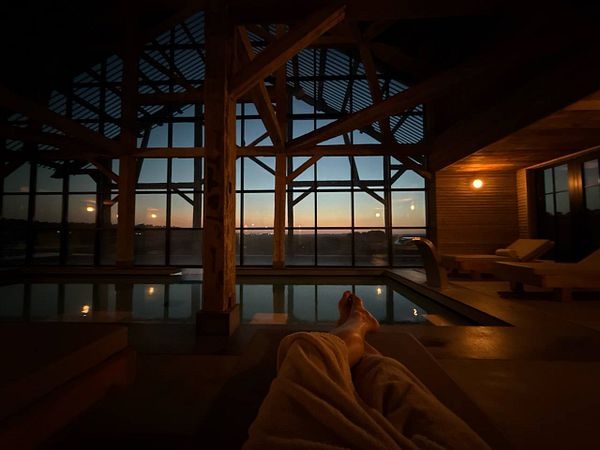 A serene indoor pool area with a view of a sunset over a rice field.