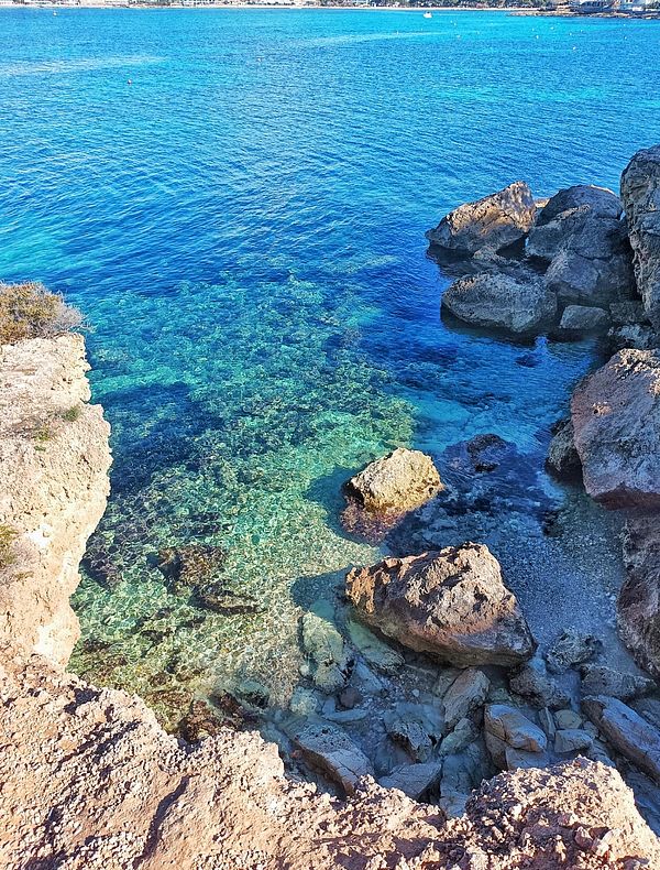 A scenic view of clear blue water and rocky shoreline.