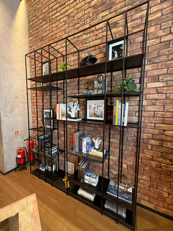 A modern shelving unit filled with decorative items and books against a brick wall.