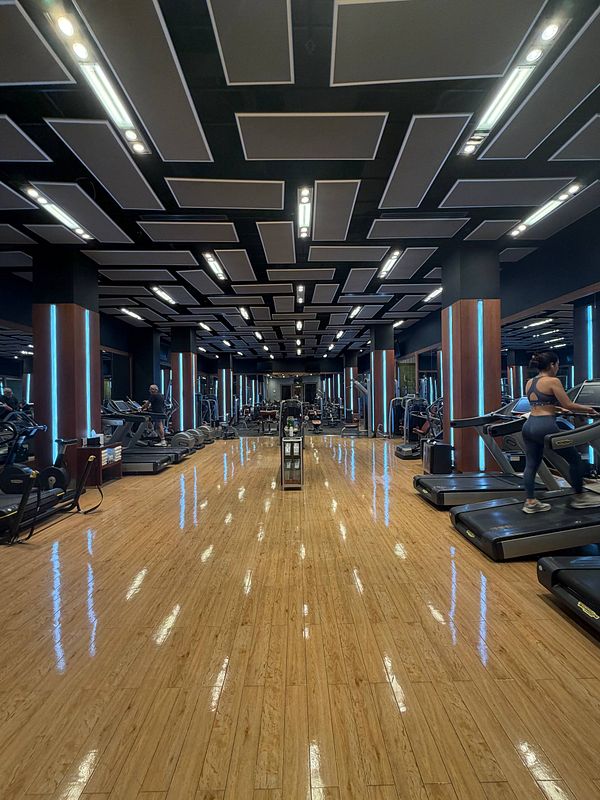 Photograph of a man lifting weights inside a gym room.