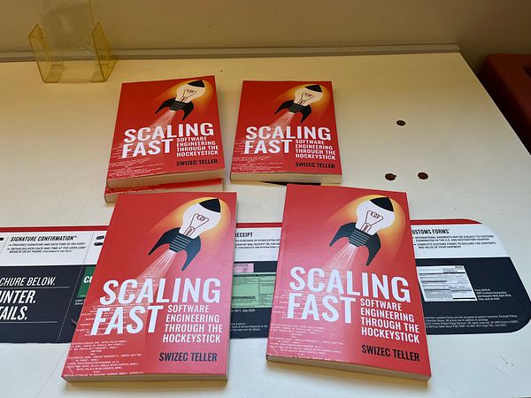 Four copies of the book 'Scaling Fast' are arranged on a table alongside some paperwork.