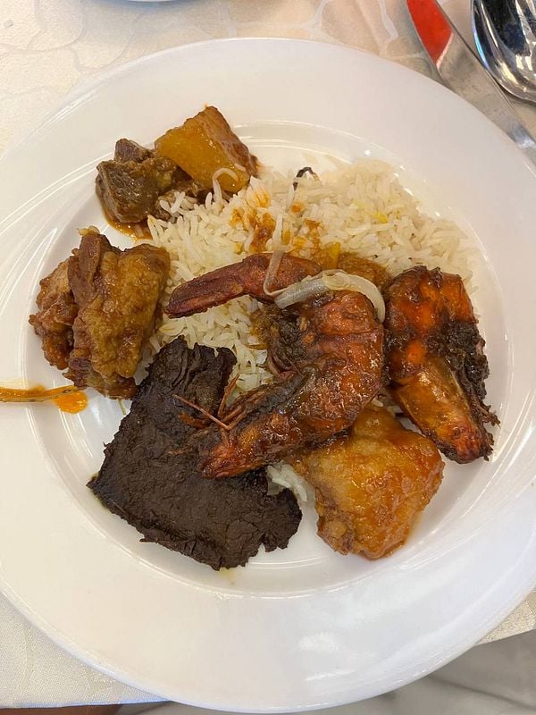 A plate of assorted dishes featuring rice, shrimp, and various meats.