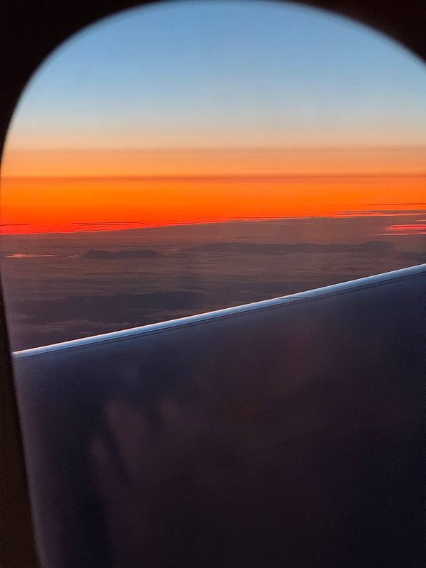 A breathtaking view of the sunset from an airplane window, showcasing vibrant colors in the sky.