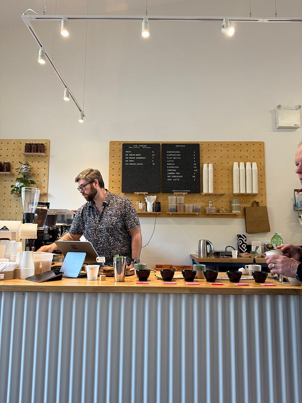 A coffee tasting event is taking place at a café with a barista serving customers.