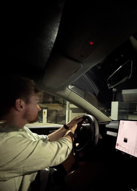 A person is practicing driving at night inside a car.