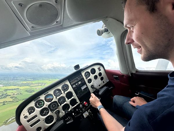 A pilot is flying a small aircraft, enjoying the view of the landscape below.