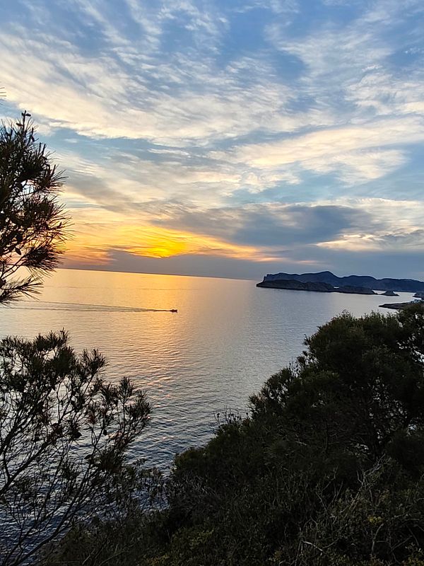 A vibrant sunset over a mountainous landscape with colorful clouds reflecting over a calm body of water.