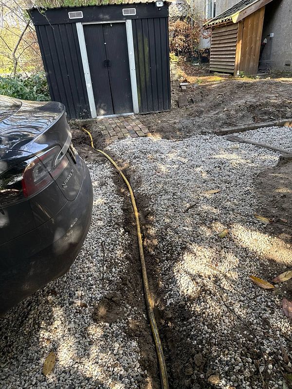 Coiled yellow garden hose laying on the ground outdoors.